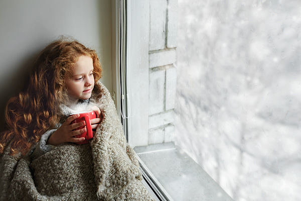 girl sitting by the window snowing